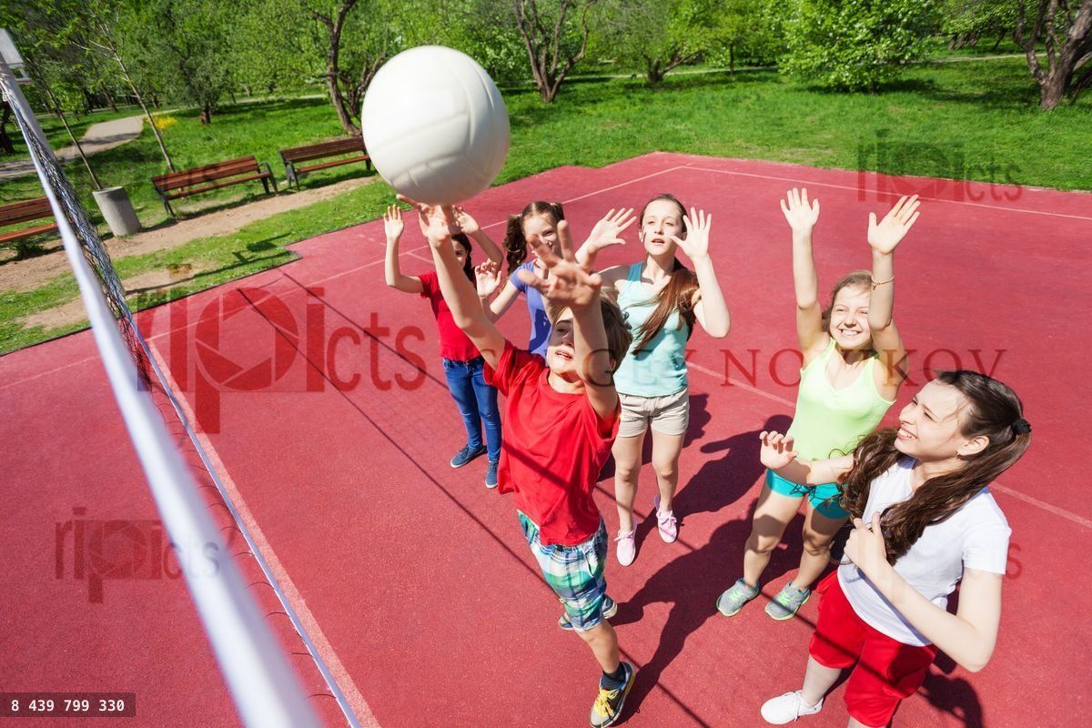Children with arms up to ball play volleyball