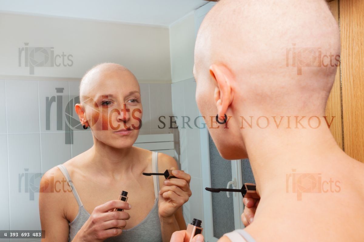 Young girl with cancer do mascara routine at bathroom mirror