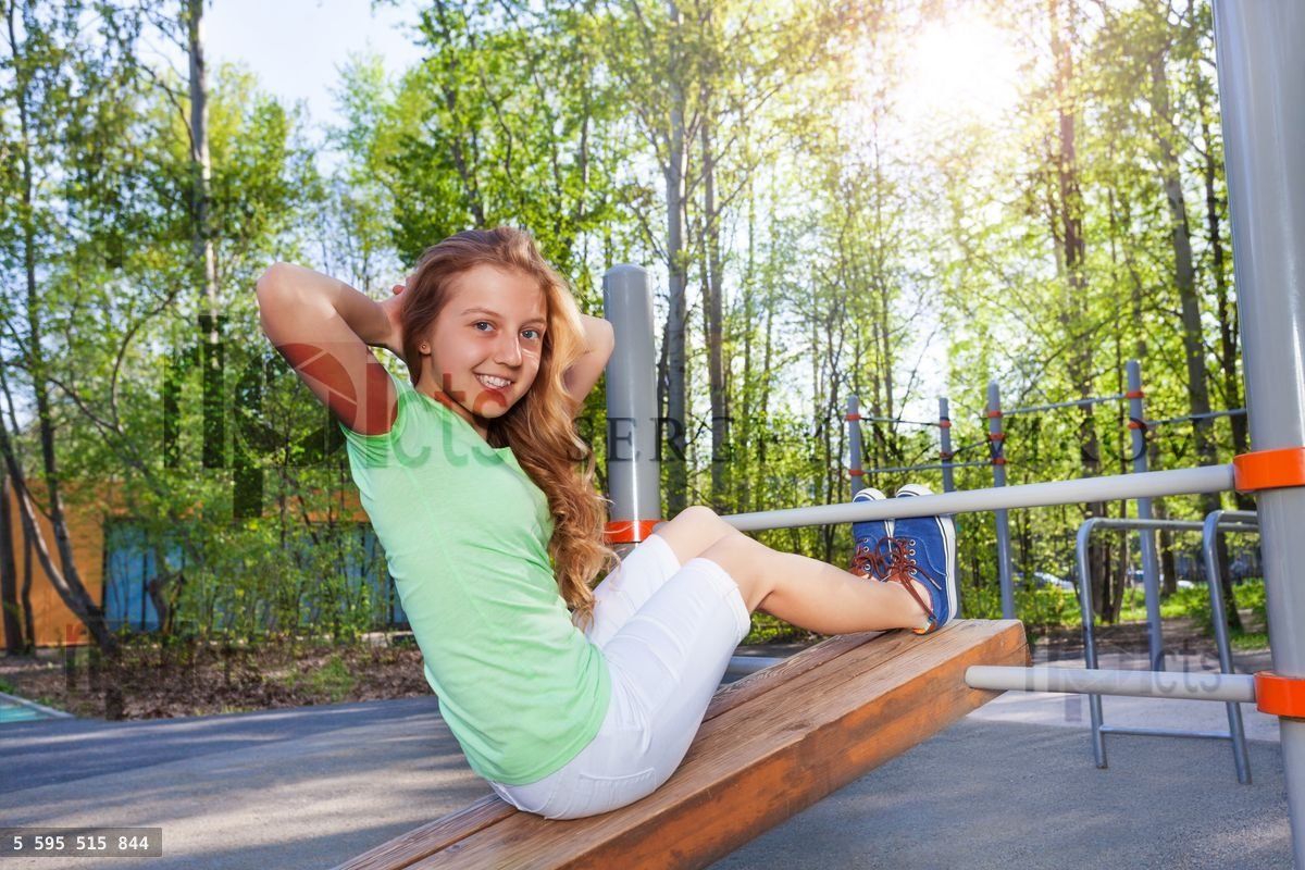 Girl does crunches on the board at sports ground