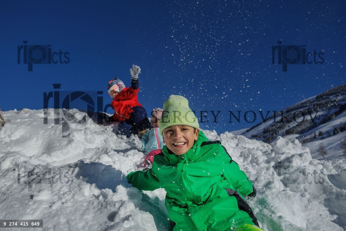 Excited children in bright clothes enjoying snowy hill adventure
