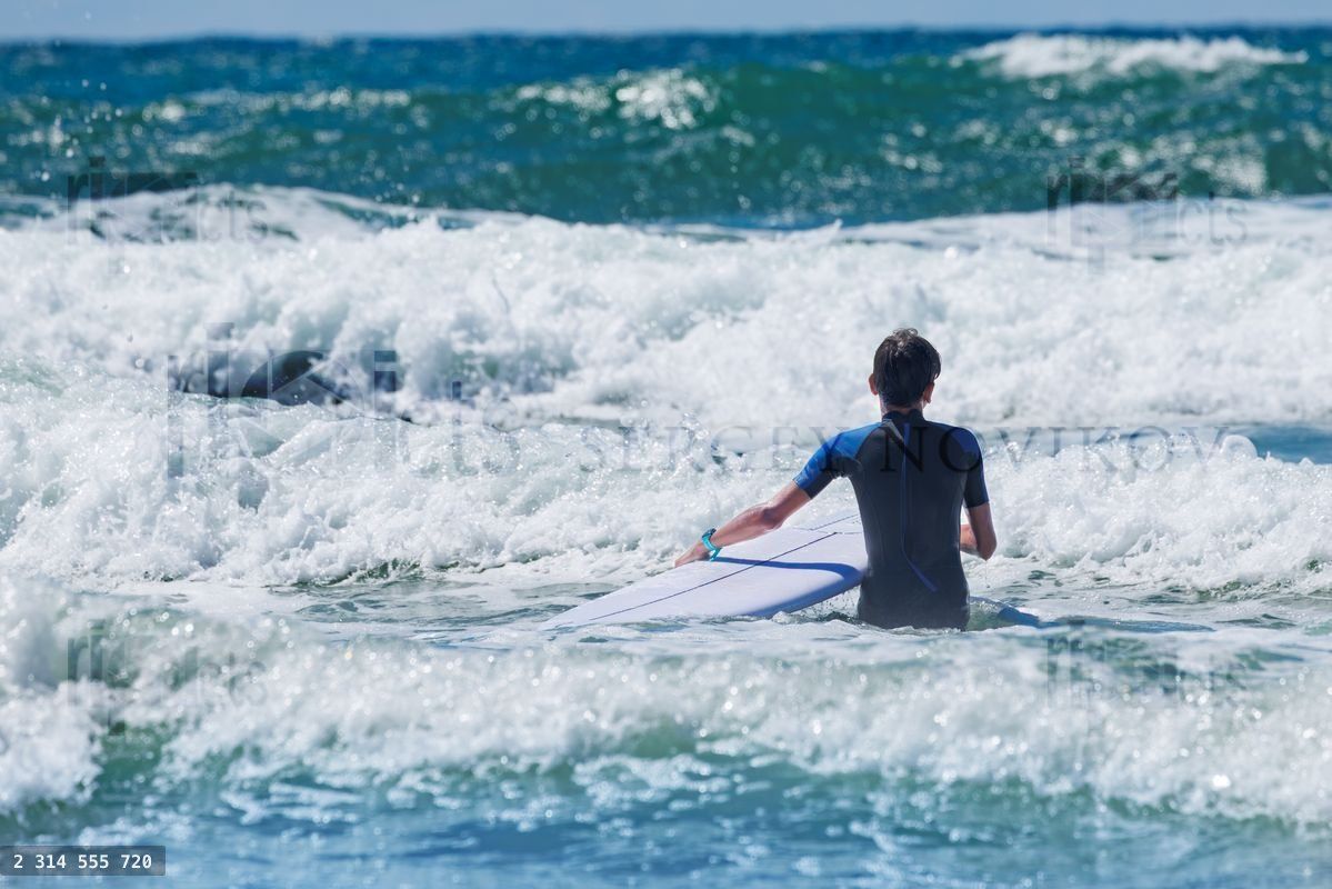 Young surfer hold board preparing to ride waves in ocean water