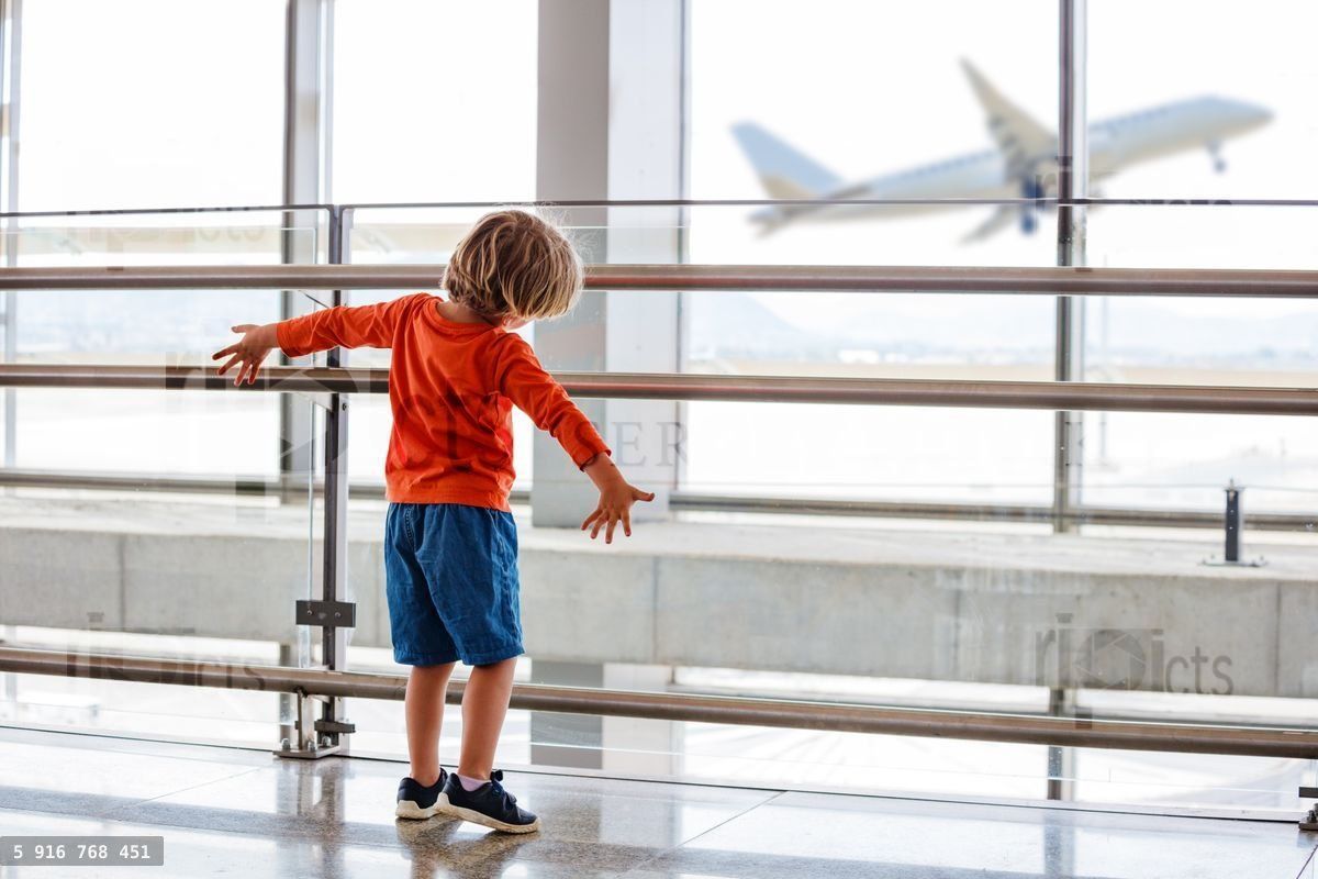 Young child watches a plane take off from an airport window
