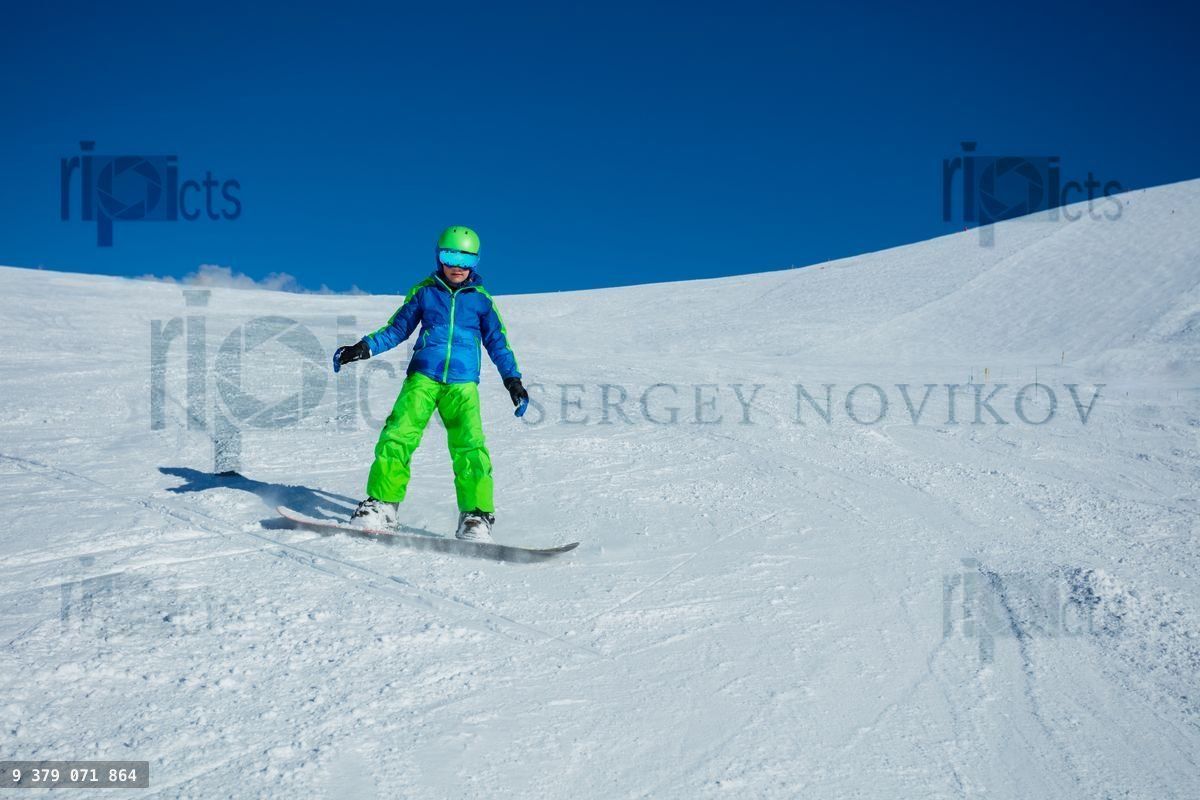 Front view action photo of boy snowboard down mountain slope
