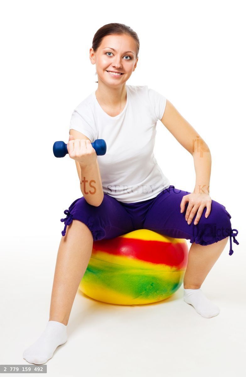 Young woman doing exercises with ball and dummbell