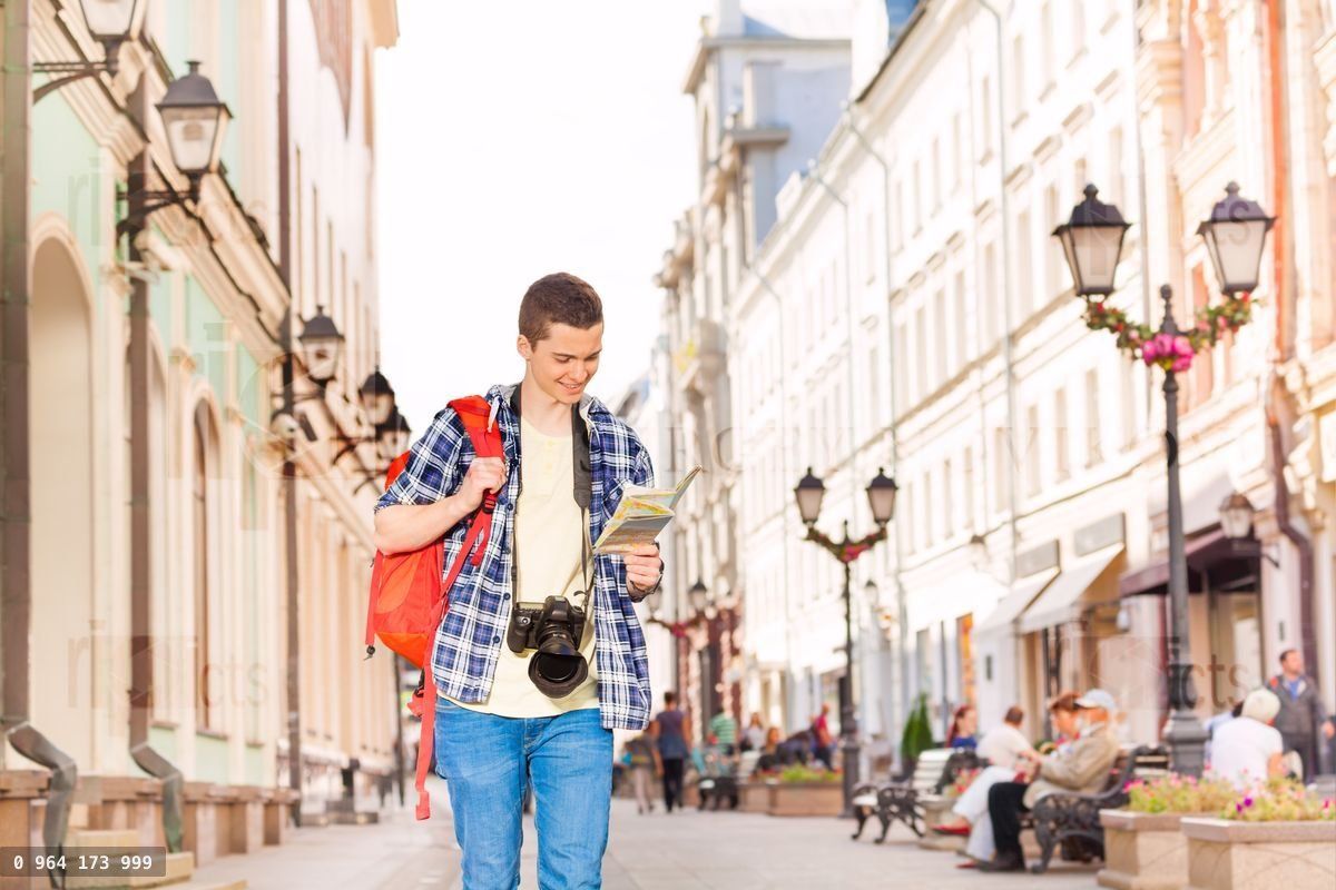 Usmívající se mladý muž s fotoaparátem a mapou města