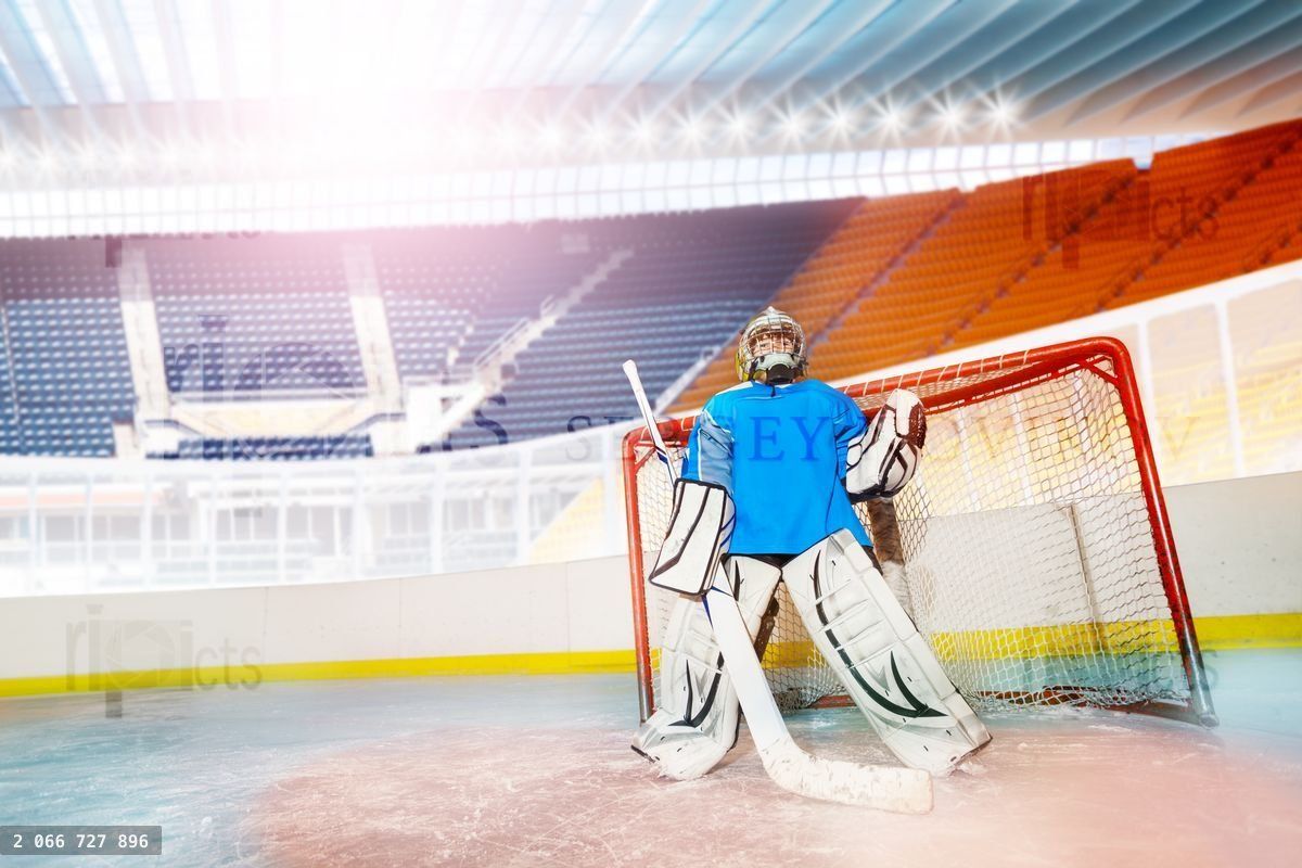 Young goalie guarding his net during hockey game