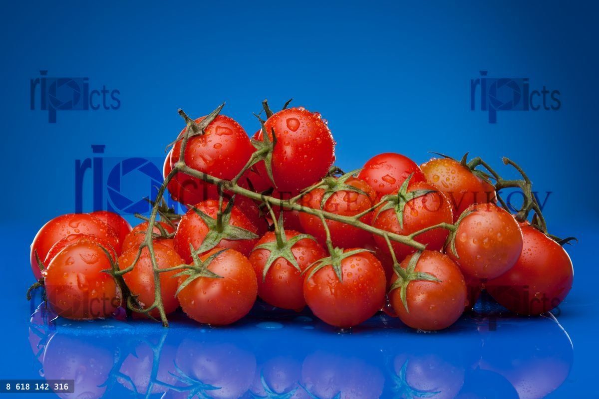 Pile of ripe cherry tomato on blue background