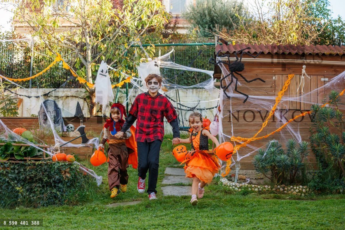 Three kids gleefully run through yard clutching candy buckets