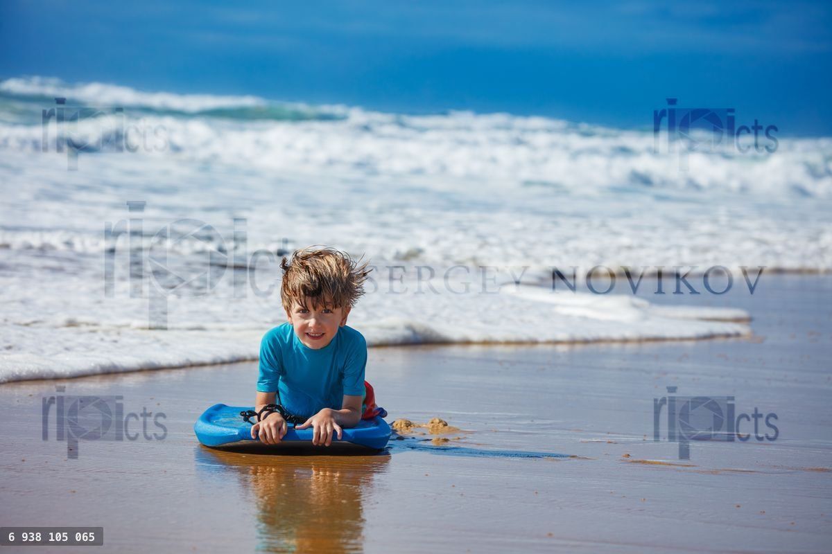 Young boy have fun bodyboarding at sunny beach day on vacations