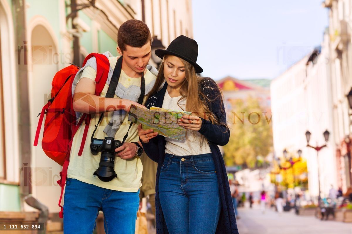 Joven hombre y joven mujer como turistas sostienen un mapa de la ciudad