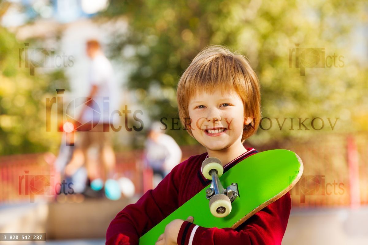 Vue rapprochée d'un garçon souriant avec un skateboard vert