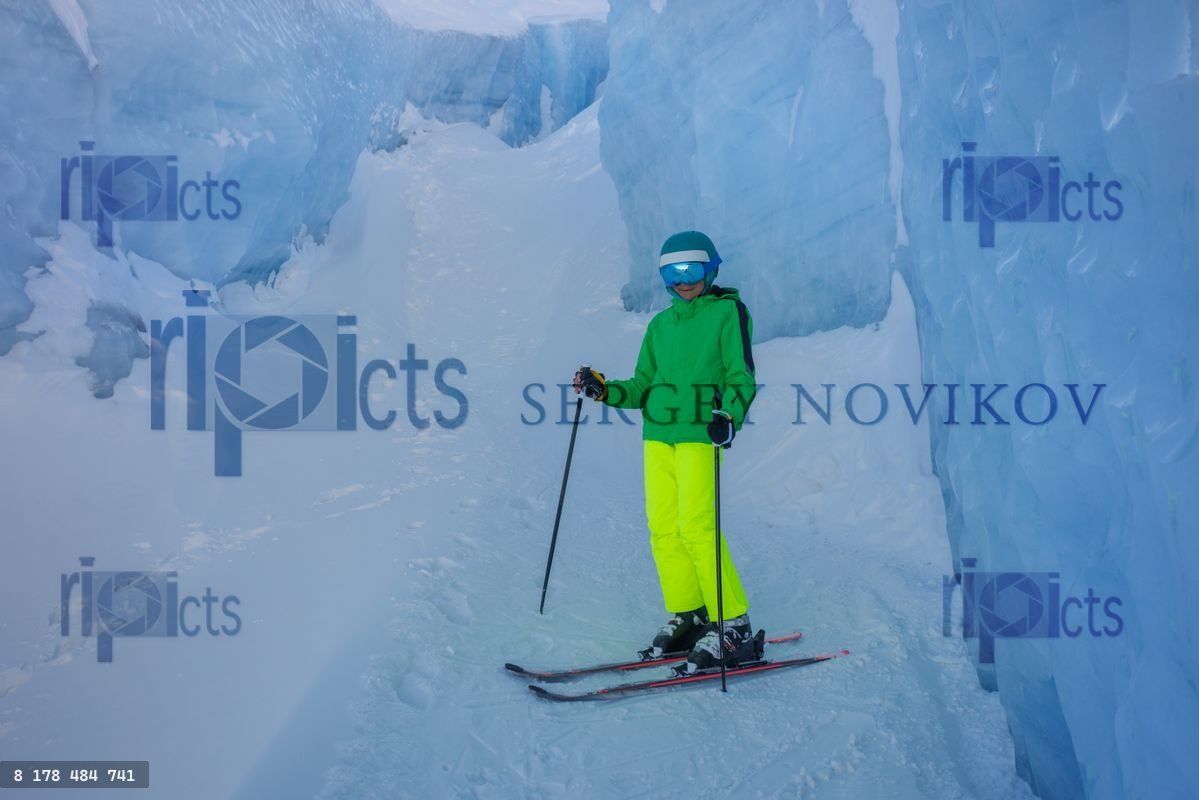 Young skier poses with skis in frozen terrain