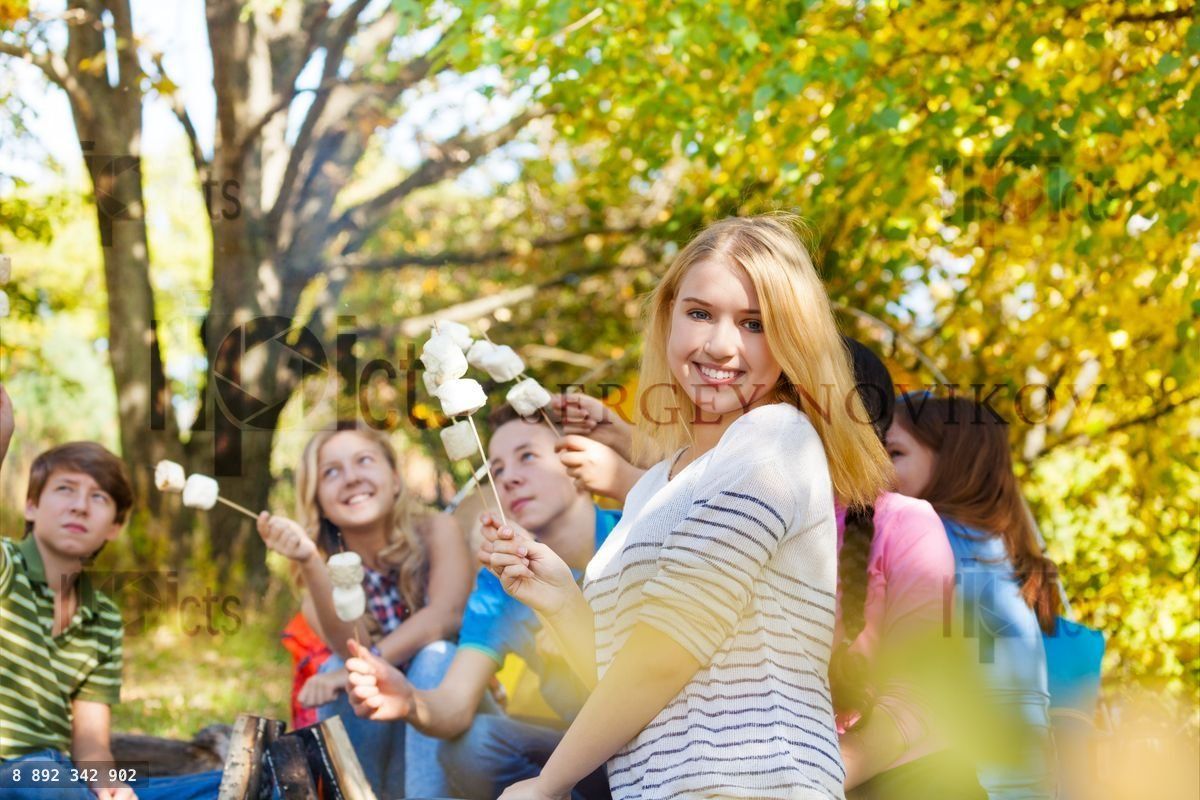 Girl and friends with marshmallow sticks sitting
