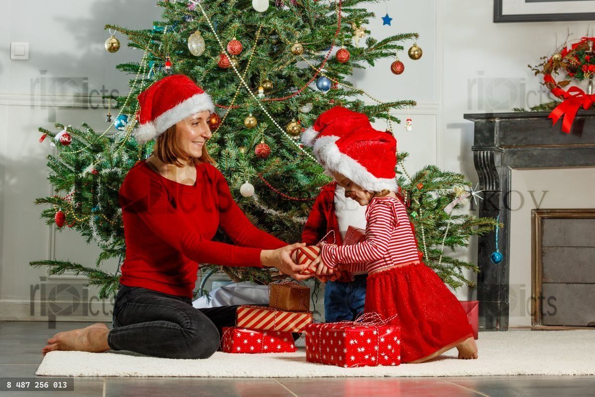Famille heureuse, maman avec enfants échangeant des cadeaux près du sapin de Noël