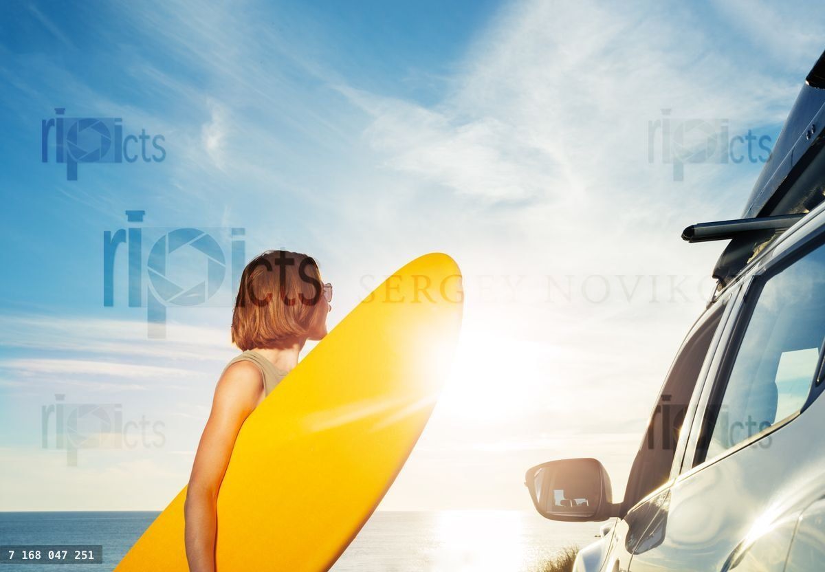 Woman with surf board by the car look on sunset over ocean