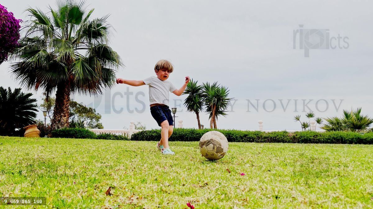 Young player boy chases soccer ball to score goal in a gate