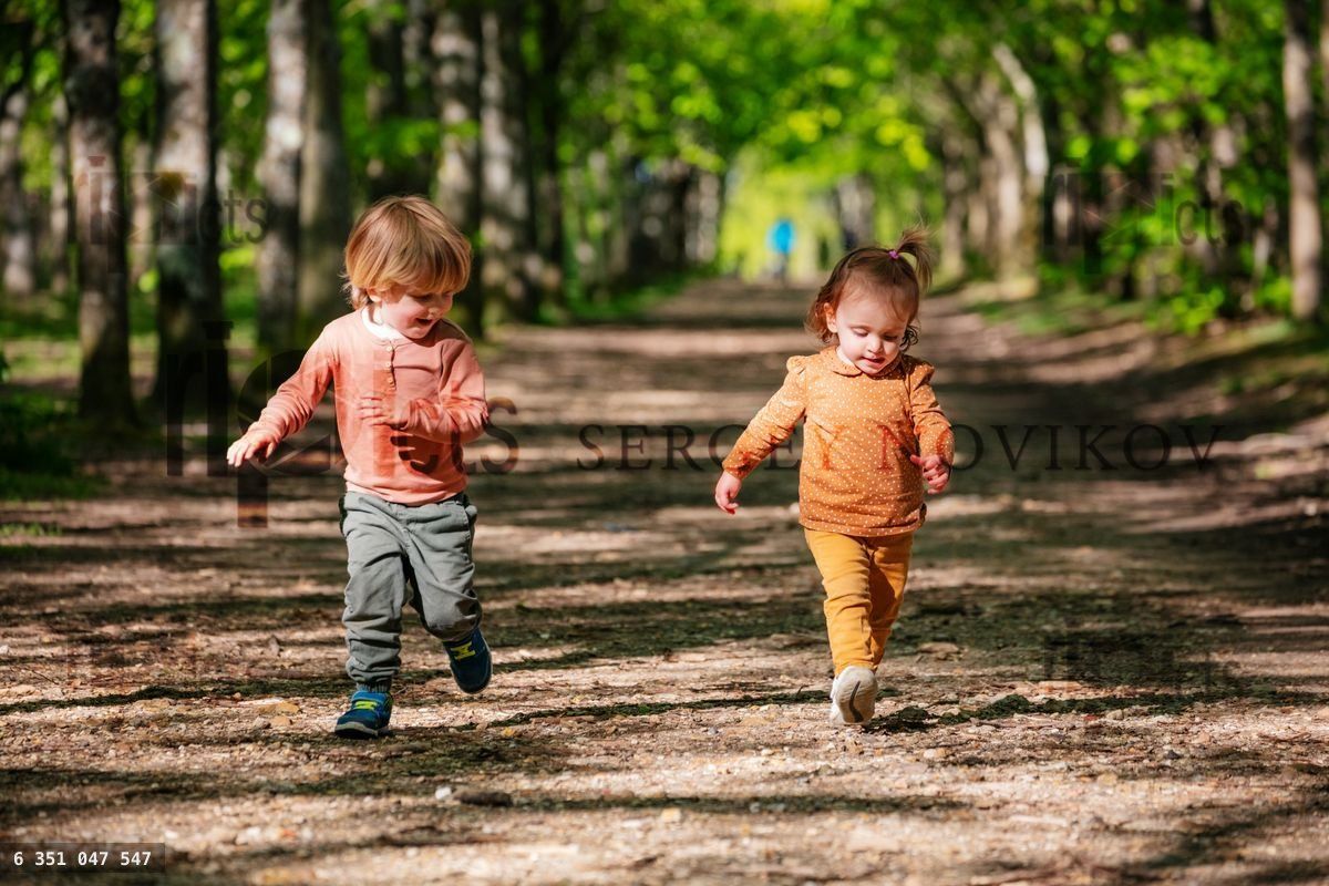 Boy and a girl run on an alley in the park at summer