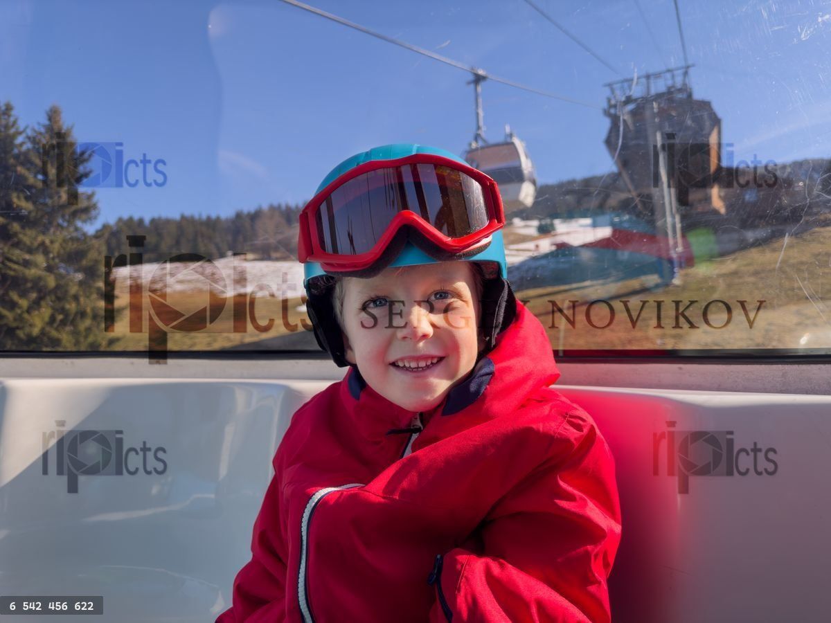 Young happy child in cable car with ski station on background