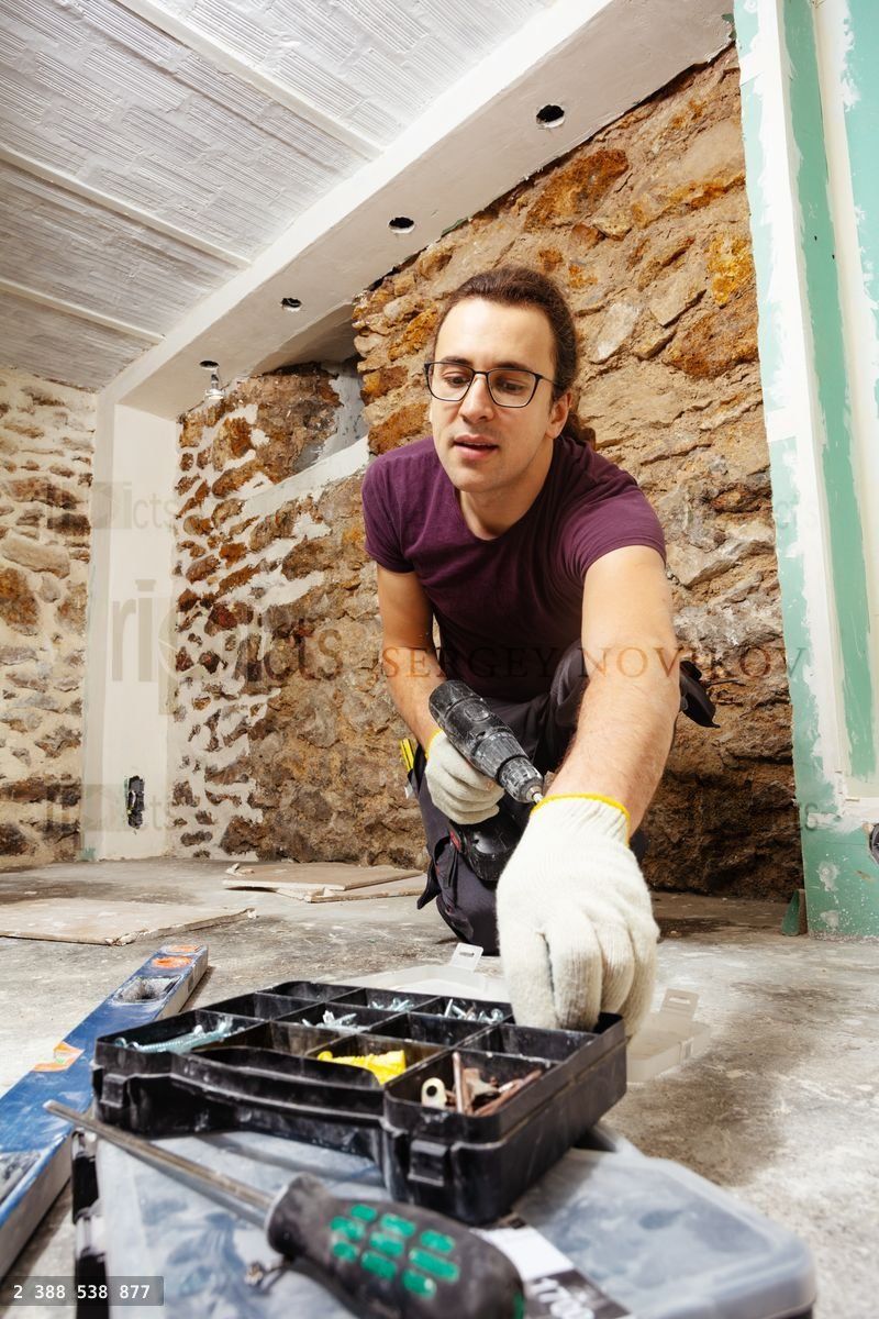 Worker man with screwdriver takes screws from box