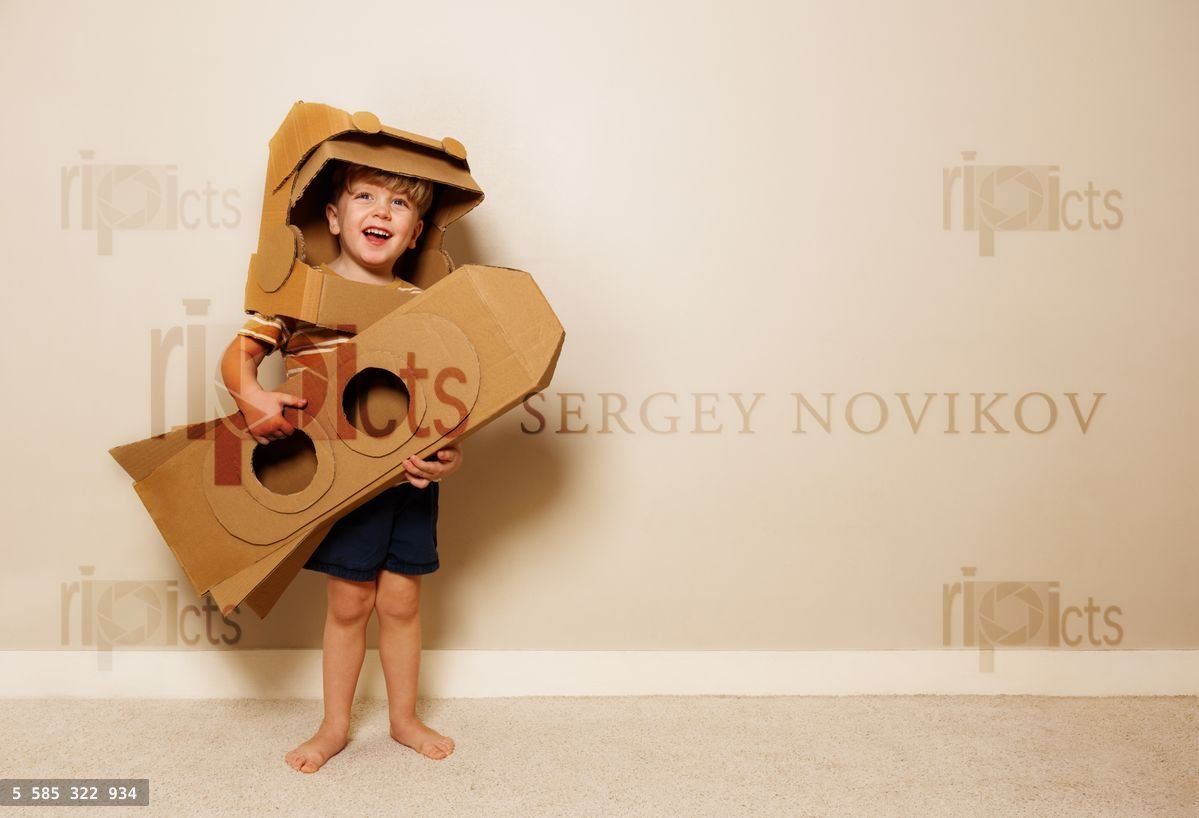Young boy holds cardboard rocket, imagines space voyage