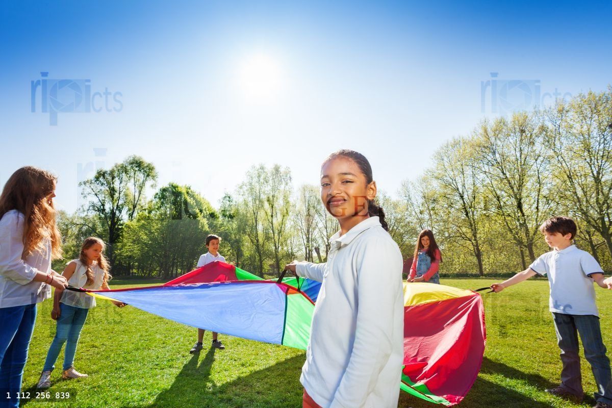 Young African girl playing parachute with friends