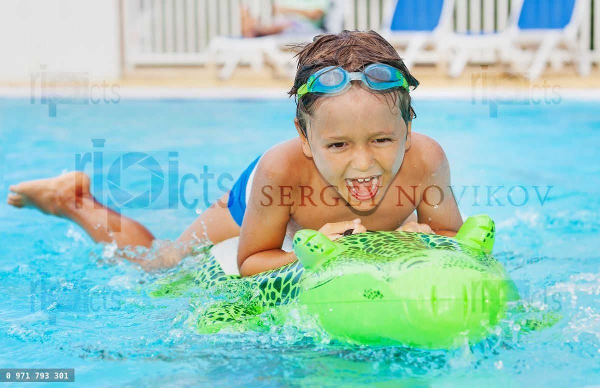 Boy having fun with inflatable toy in pool
