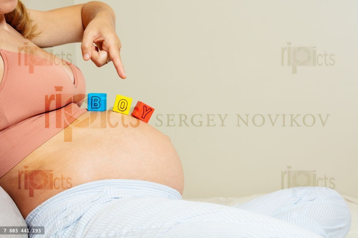 Woman points finger to boy word on pregnant belly