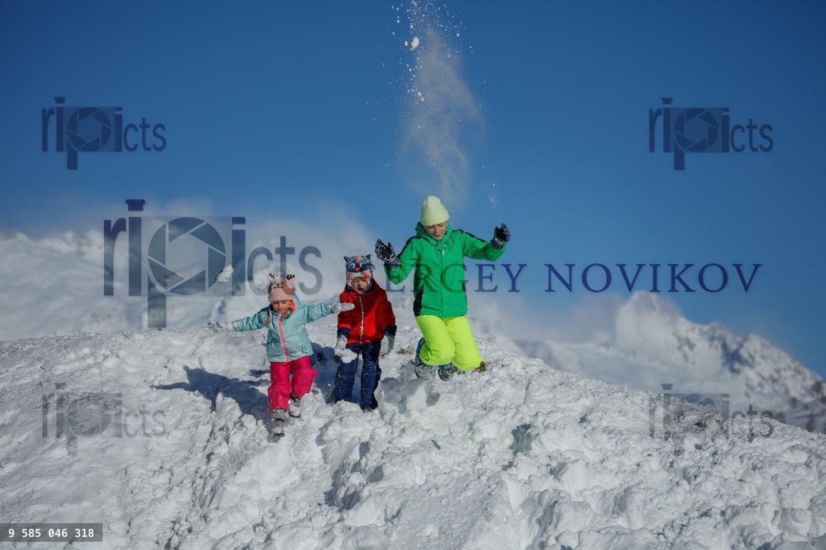 Des enfants courent sur une colline enneigée en riant sous un ciel bleu clair