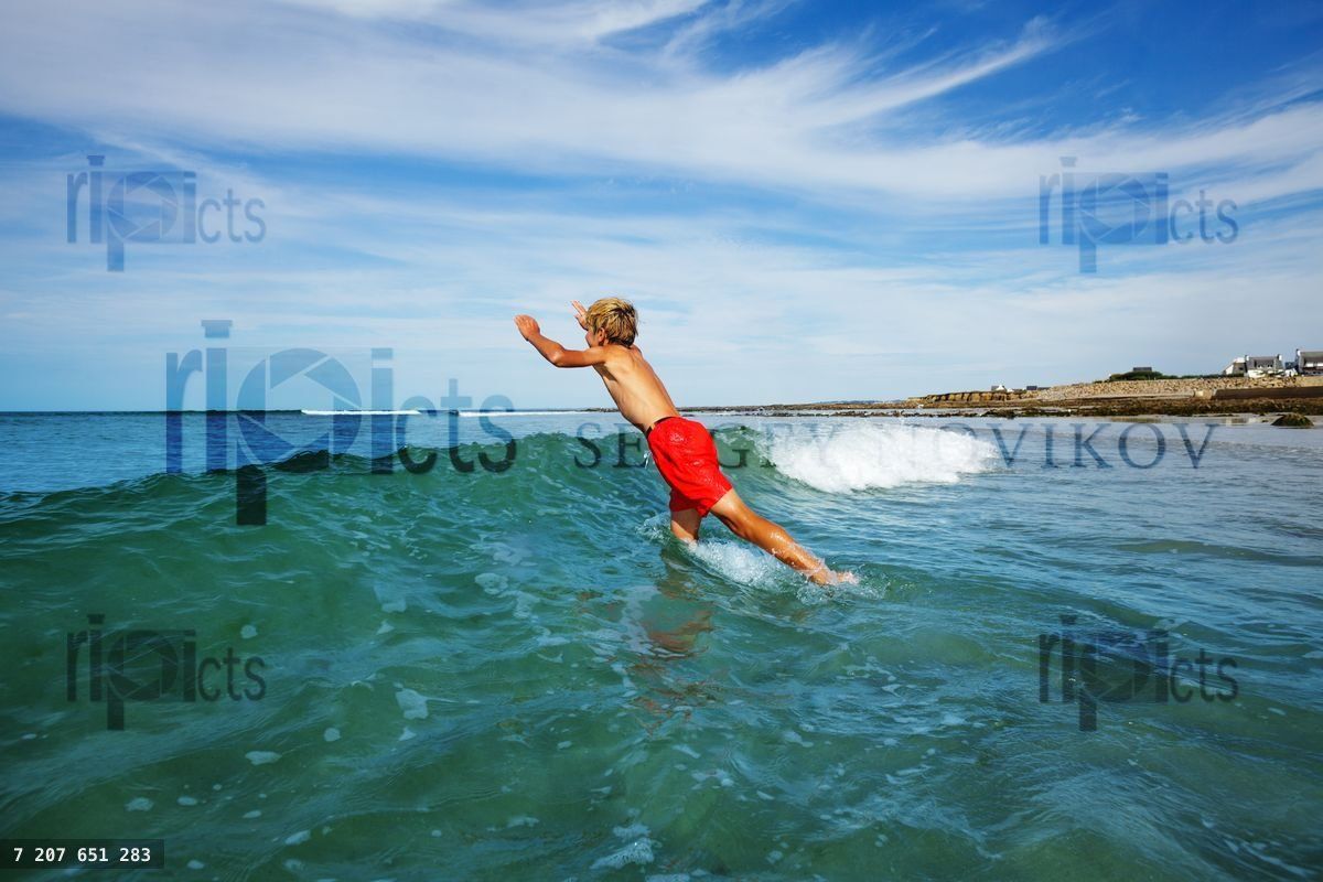 Boy jump running into ocean wave on the summer beach