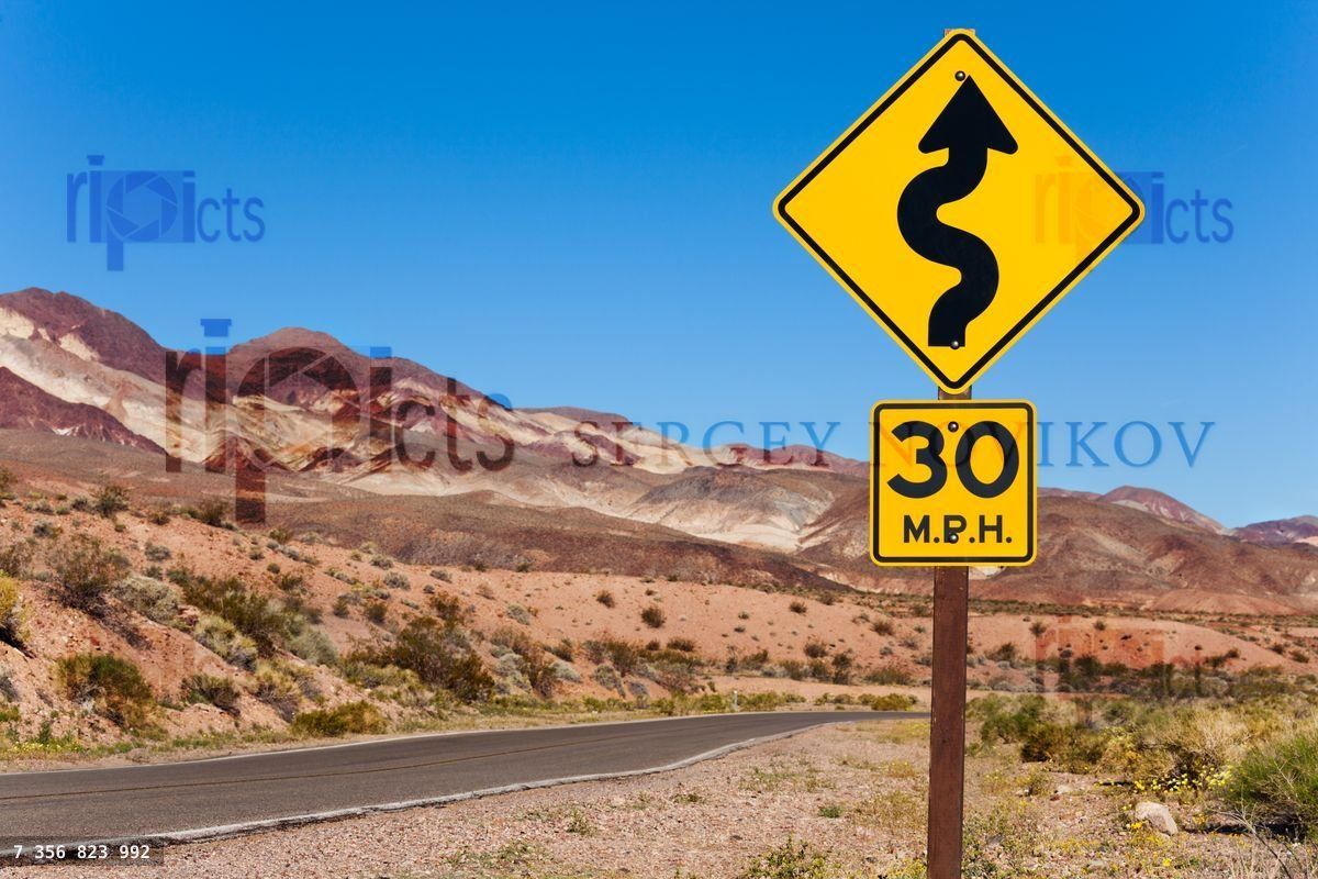 Yellow sign with curved arrow and road, California