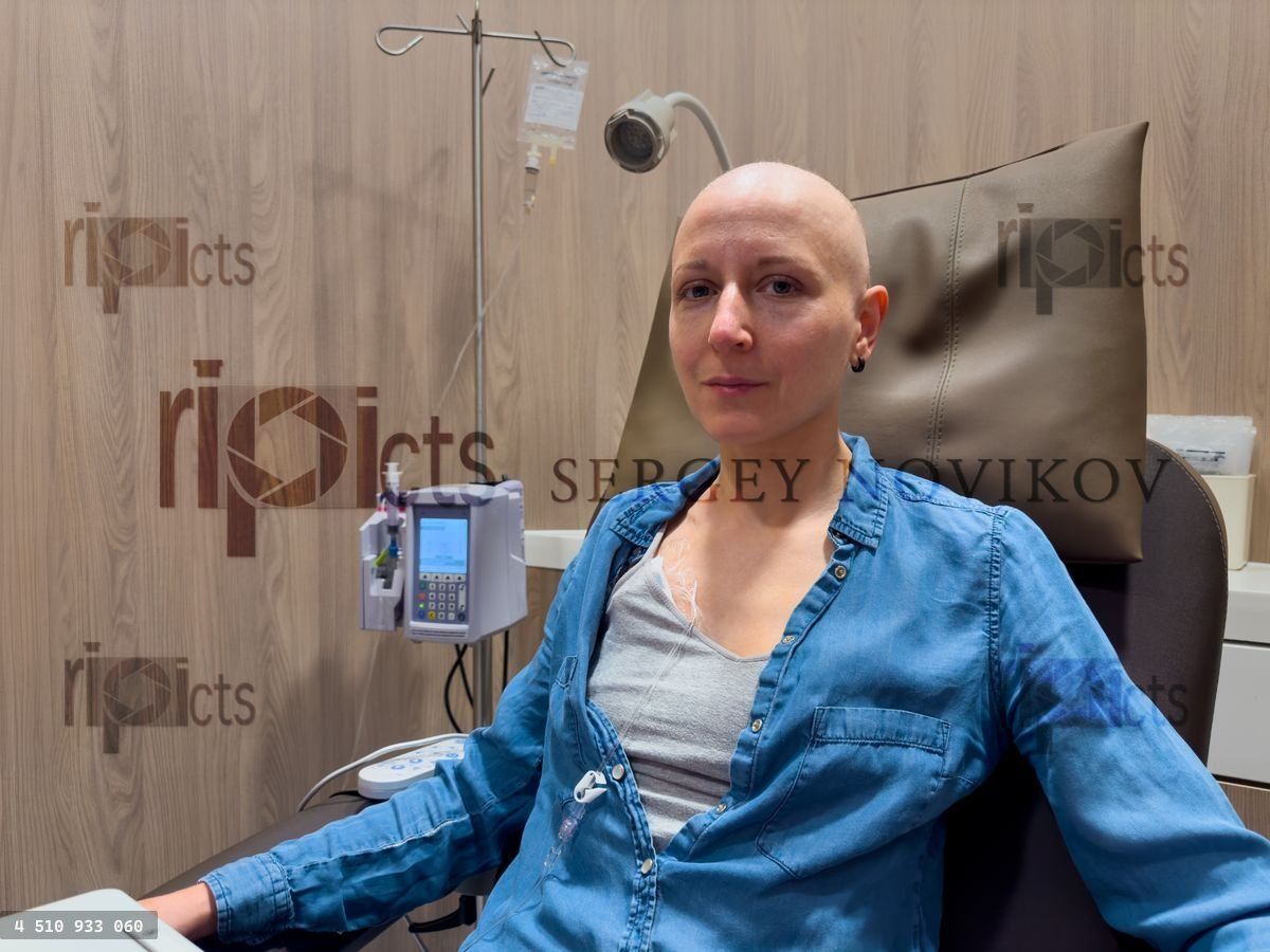Woman in chemotherapy session sit bravely with IV drip attached
