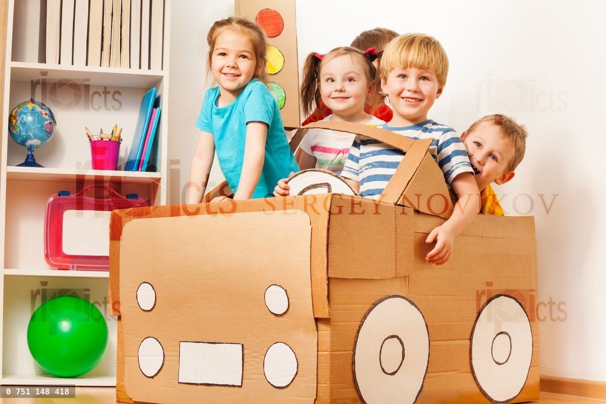 Young boy driving his friends in cardboard car