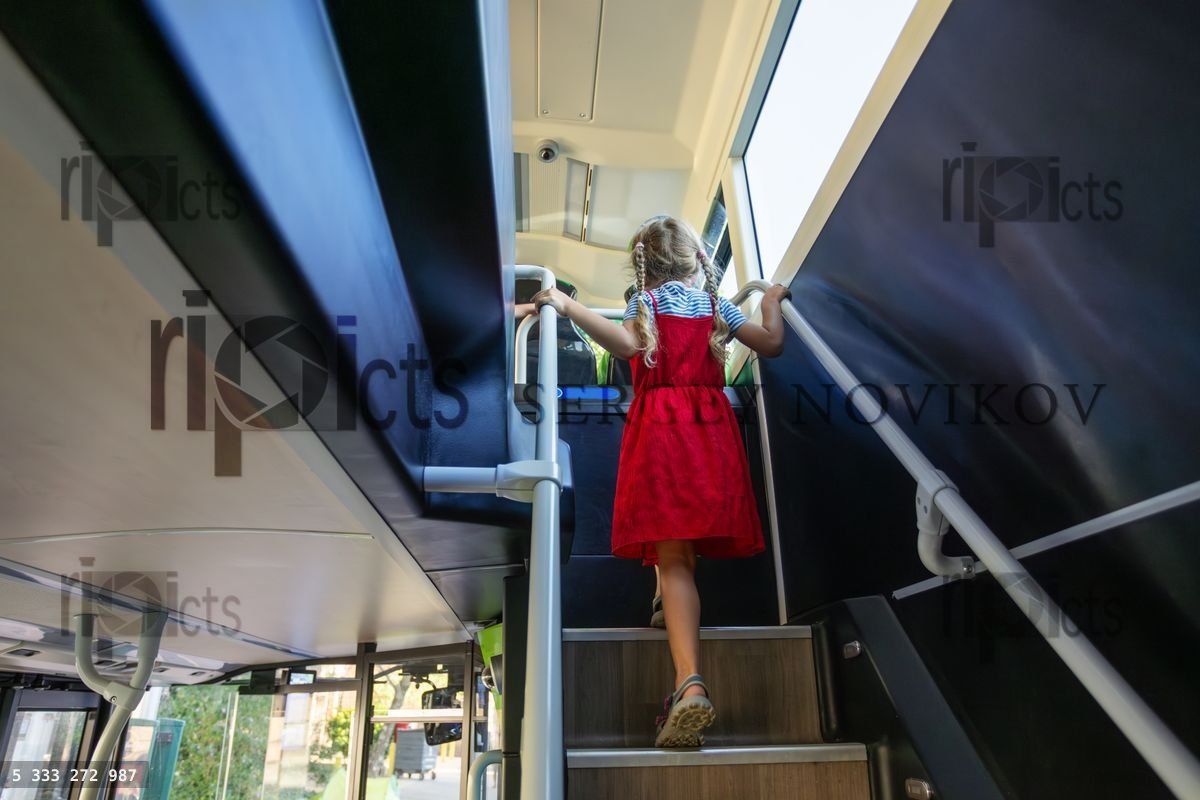 Young girl climb stairs inside a modern public double decker bus
