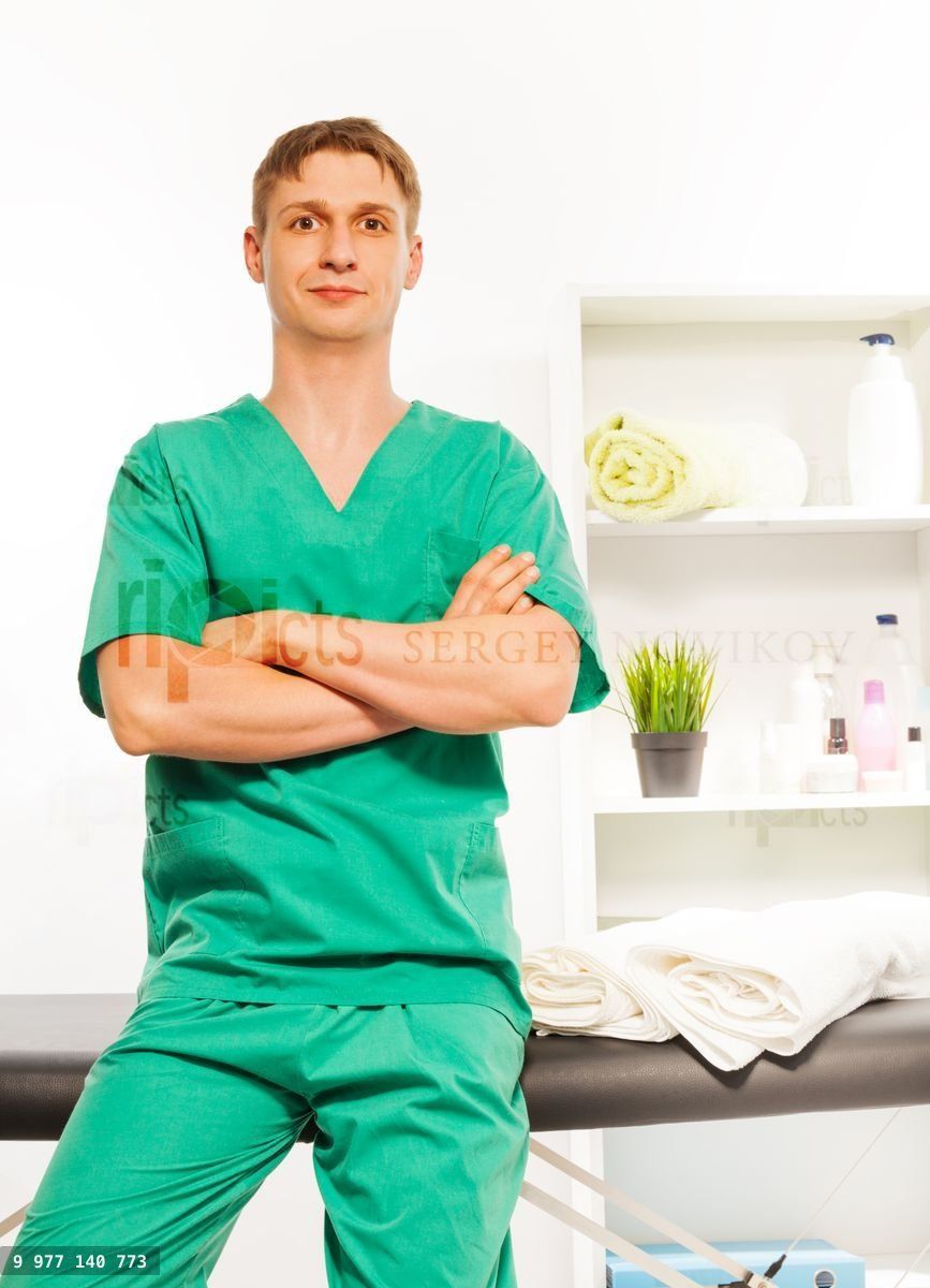Young masseur in uniform sitting on massage couch