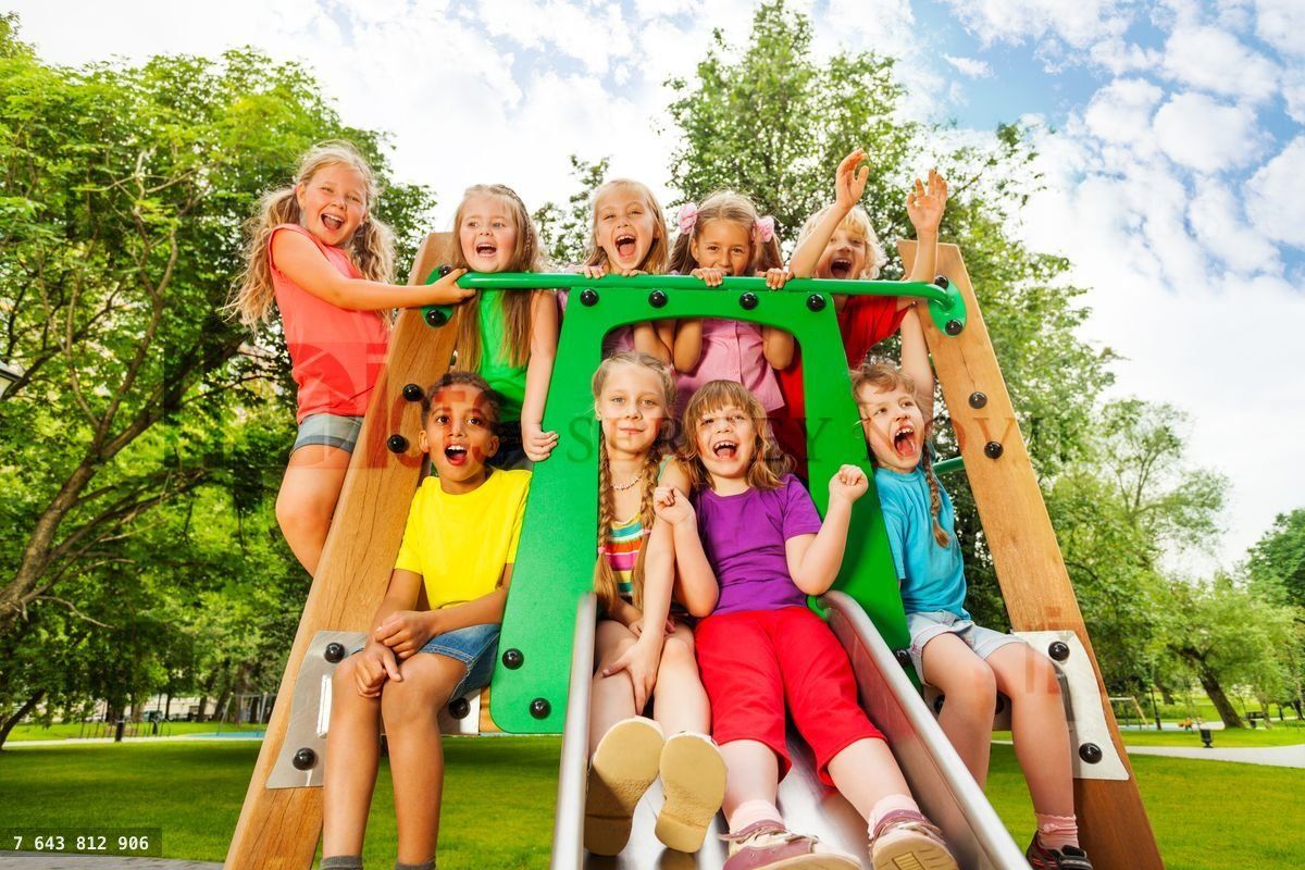 Funny children on playground chute with arms up