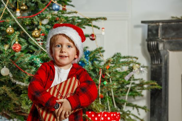 Little boy in a Santa hat hold his Christmas present and smile