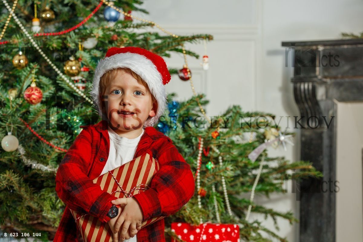 Little boy in a Santa hat hold his Christmas present and smile
