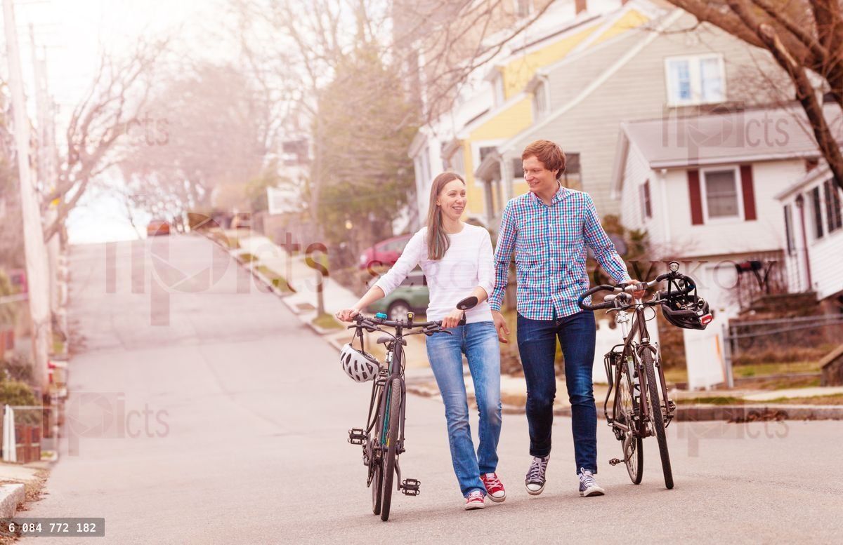 Young smiling couple walk with bicycles outside