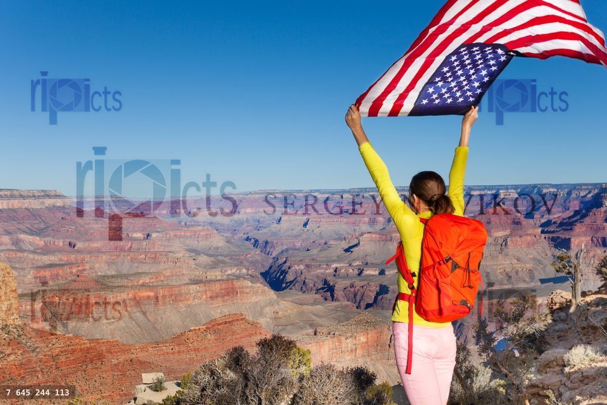 Woman with rucksack holding American flag, USA