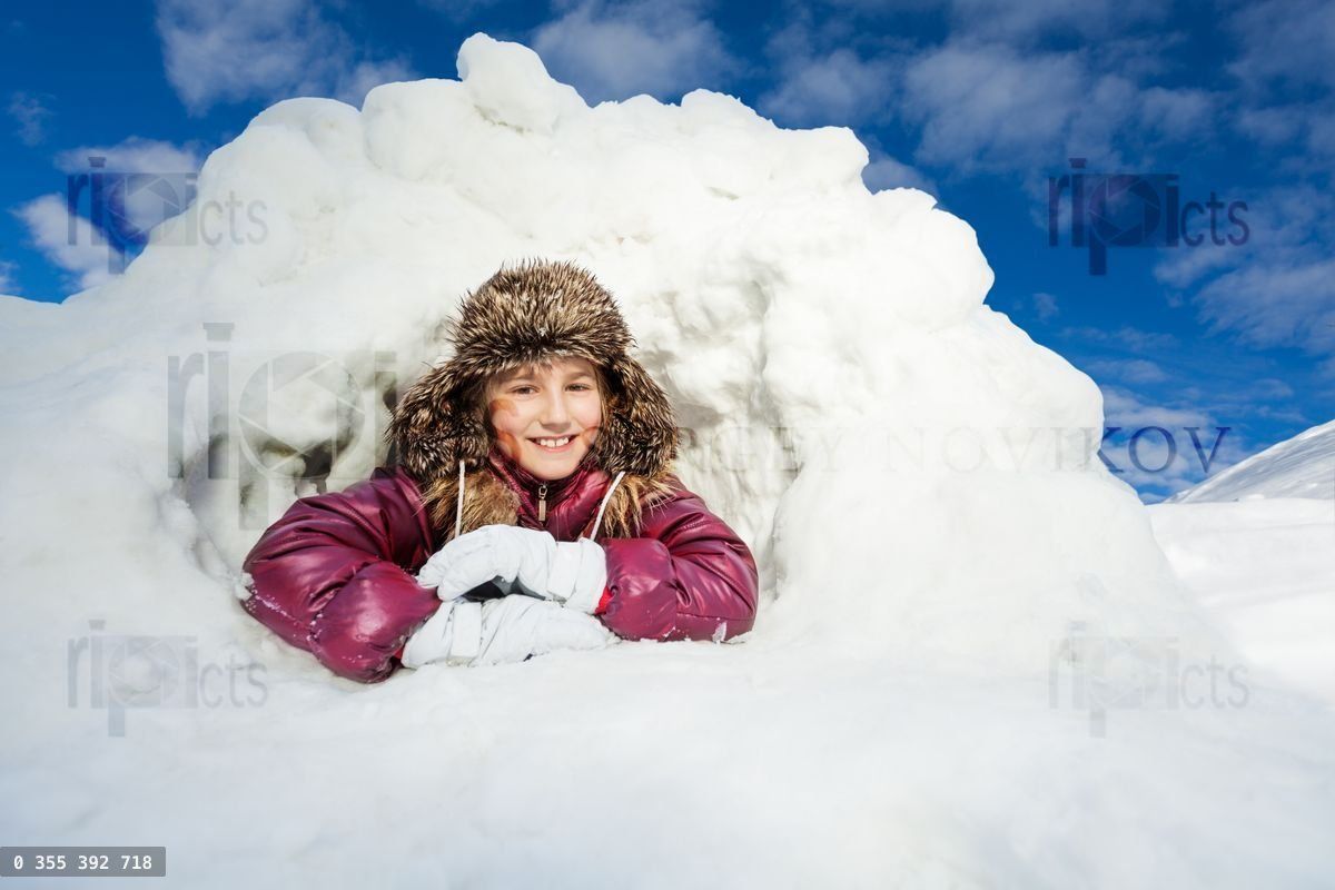 Girl having fun in snow cave at winter day