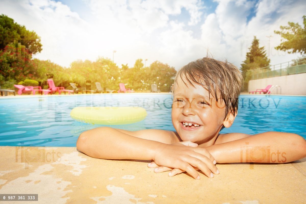 Happy boy relaxing at the swimming pool edge