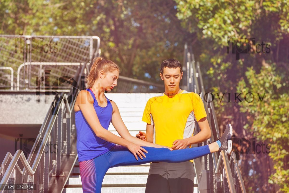 Young man helping his girl friend stretching legs