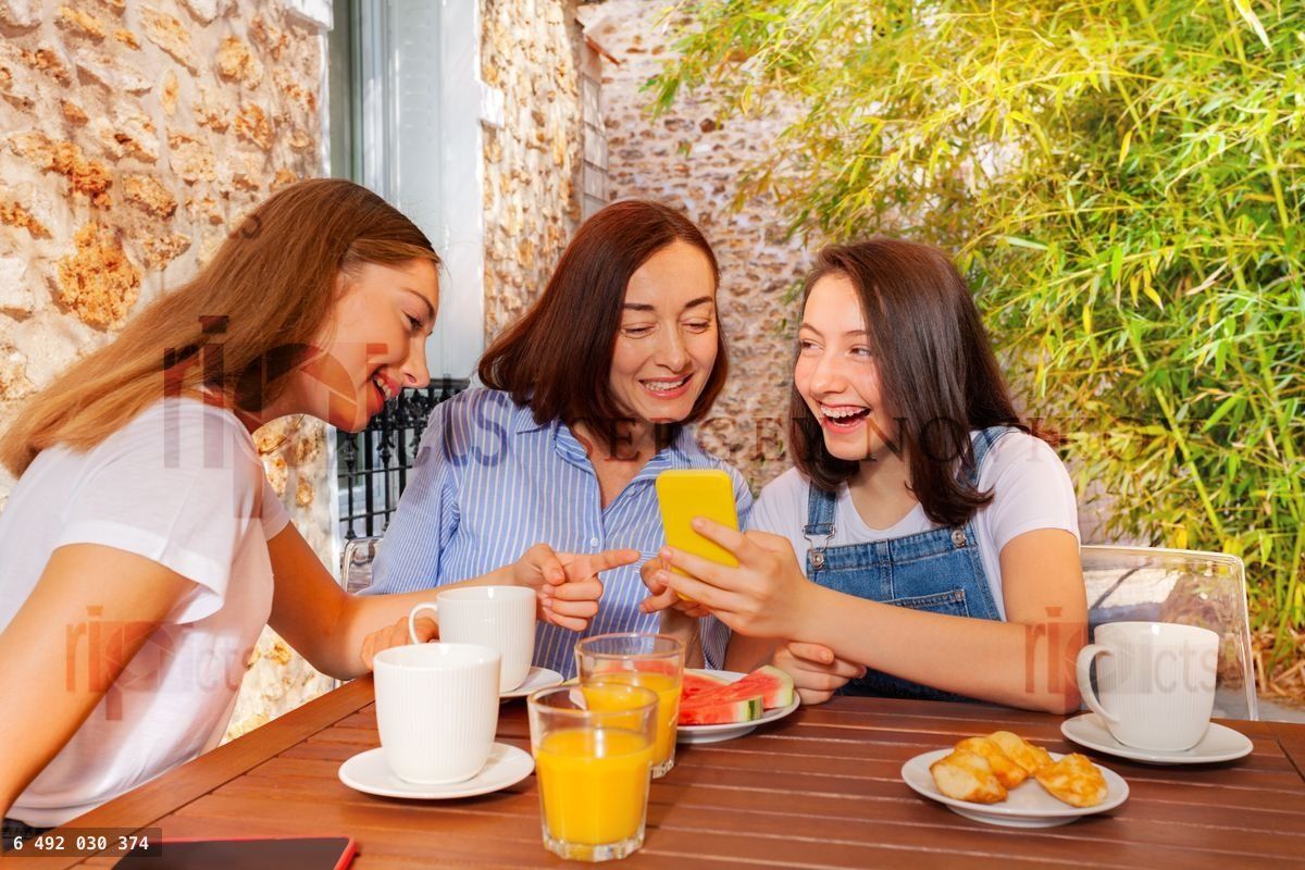 Girl having family breakfast and using smartphone