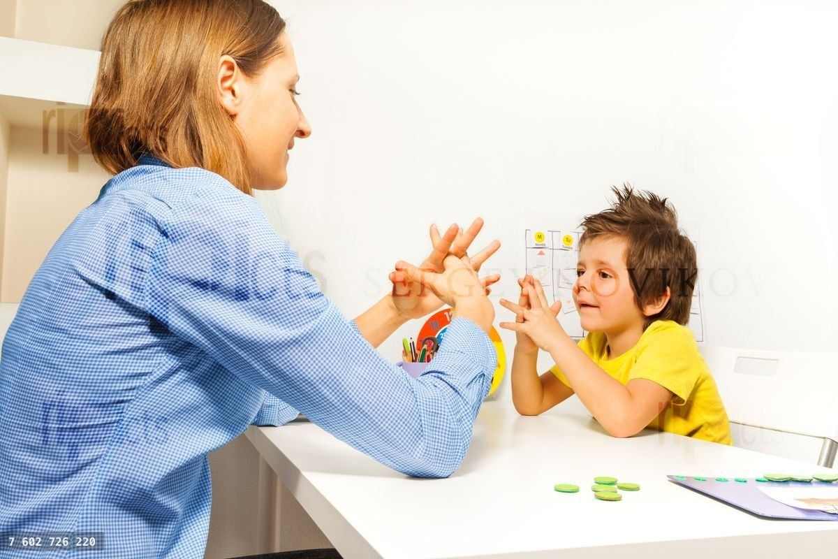 Boy exercises putting fingers with therapist