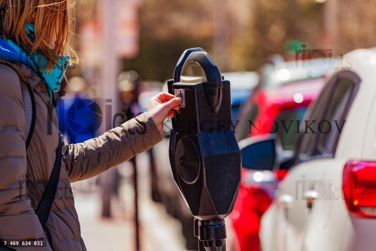 Woman pay parking on in street park meter pole