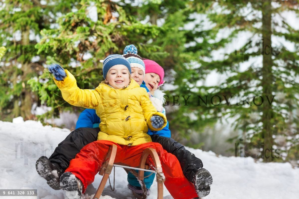 Children winter fun on sledge sliding down