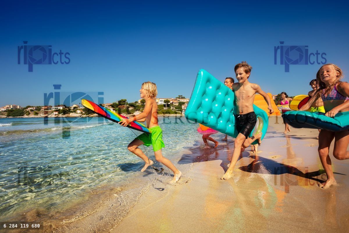 Young surfer running into the sea with friends