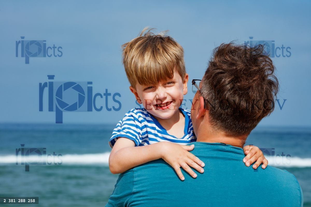 Young boy and his dad share a happy moment by the beach waves