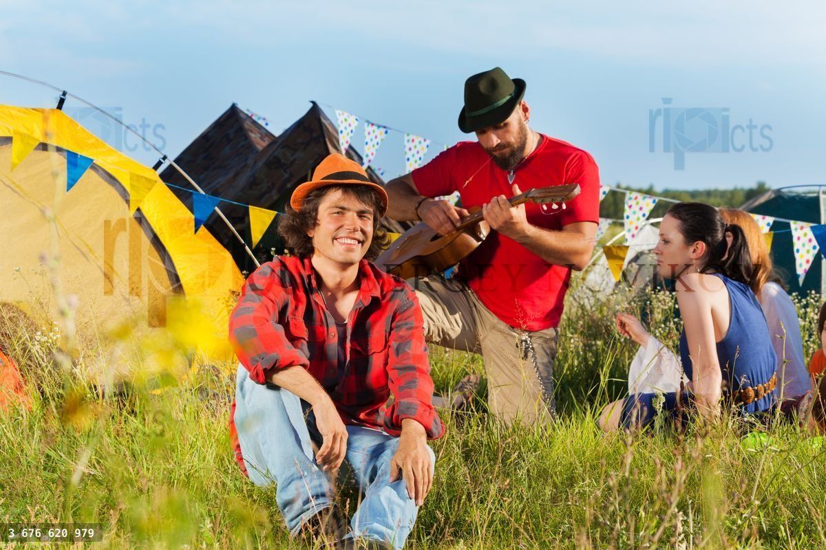 Young man sitting on grass at fest with friends