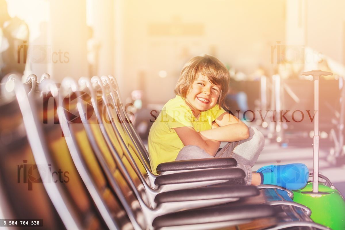 Happy boy sitting on the seat at airport terminal